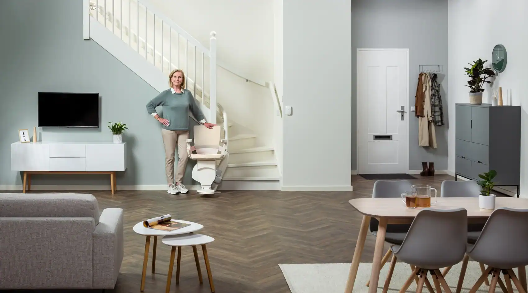 Woman standing beside an Otolift stairlift at an indoor landing